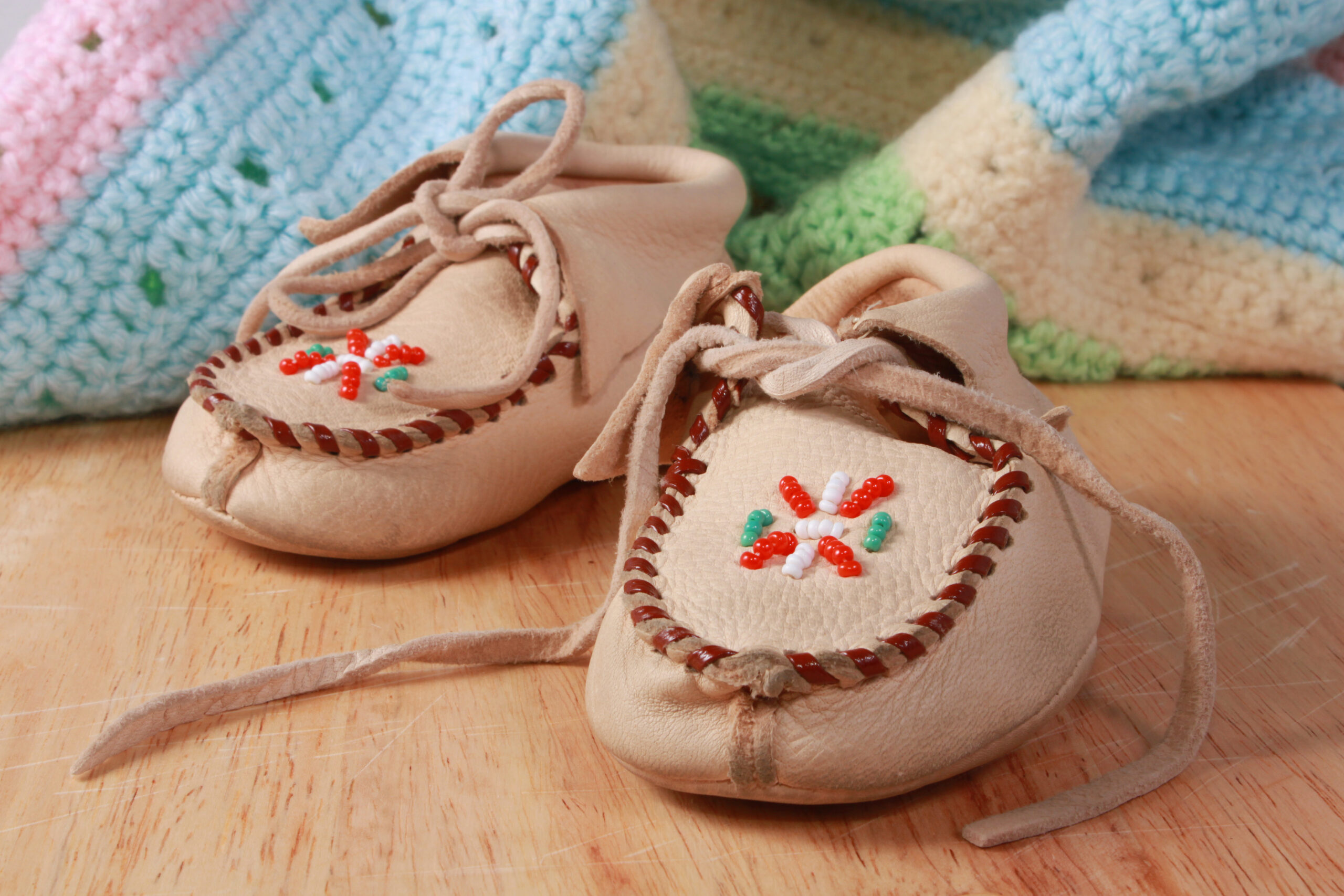 A close-up photo of a pair of baby moccasins with red, green and white beading.